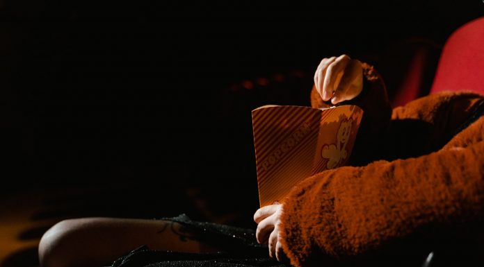 A person enjoying popcorn during a movie at an indoor cinema, sitting comfortably.