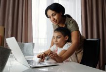 A mother helps her daughter with an online lesson on a laptop, showcasing family bonding and education at home.