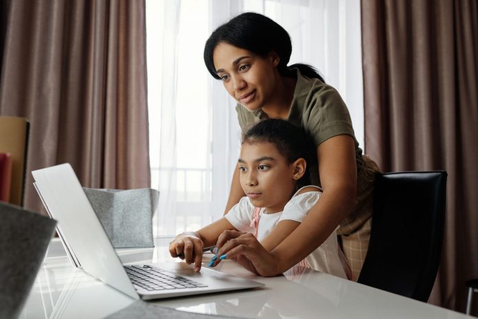 como-inscribir-a-tu-hijo-en-las-escuelas-de-north- A mother helps her daughter with an online lesson on a laptop, showcasing family bonding and education at home.