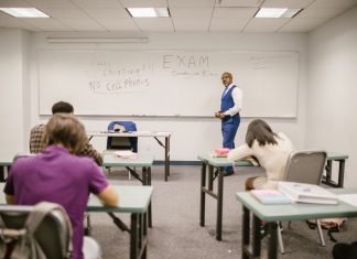 A college educator proctoring an exam, enforcing no cheating rules.