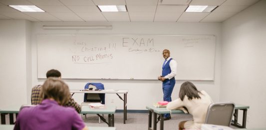 A college educator proctoring an exam, enforcing no cheating rules.