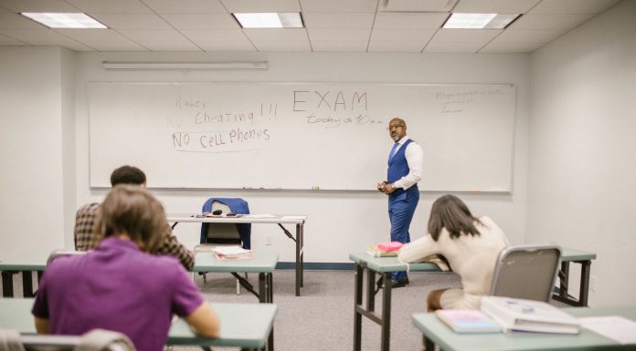 A college educator proctoring an exam, enforcing no cheating rules.