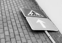 Disabled students at Dickinson High went nearly a year without an elevator. The district withheld records. Black and white photo of a fallen street sign on a brick sidewalk.