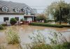 Flood Watch Issued for Jersey City as Storm System Approaches A suburban house surrounded by floodwaters after heavy rain, showing impact of natural disaster.
