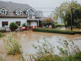A suburban house surrounded by floodwaters after heavy rain, showing impact of natural disaster.