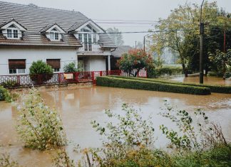 A suburban house surrounded by floodwaters after heavy rain, showing impact of natural disaster.