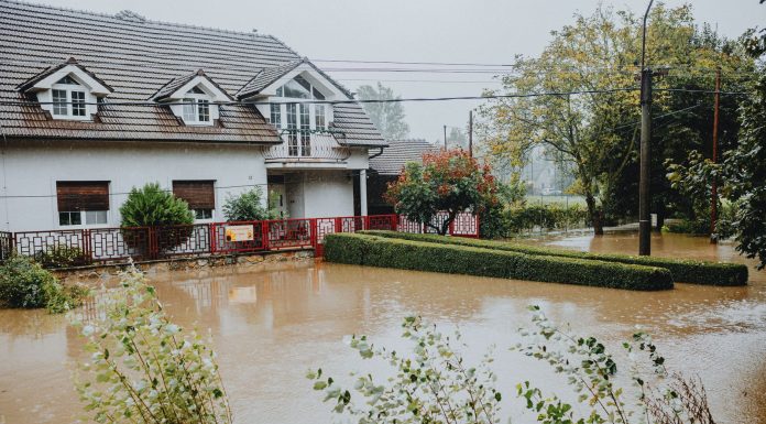 A suburban house surrounded by floodwaters after heavy rain, showing impact of natural disaster.