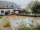 A suburban house surrounded by floodwaters after heavy rain, showing impact of natural disaster.