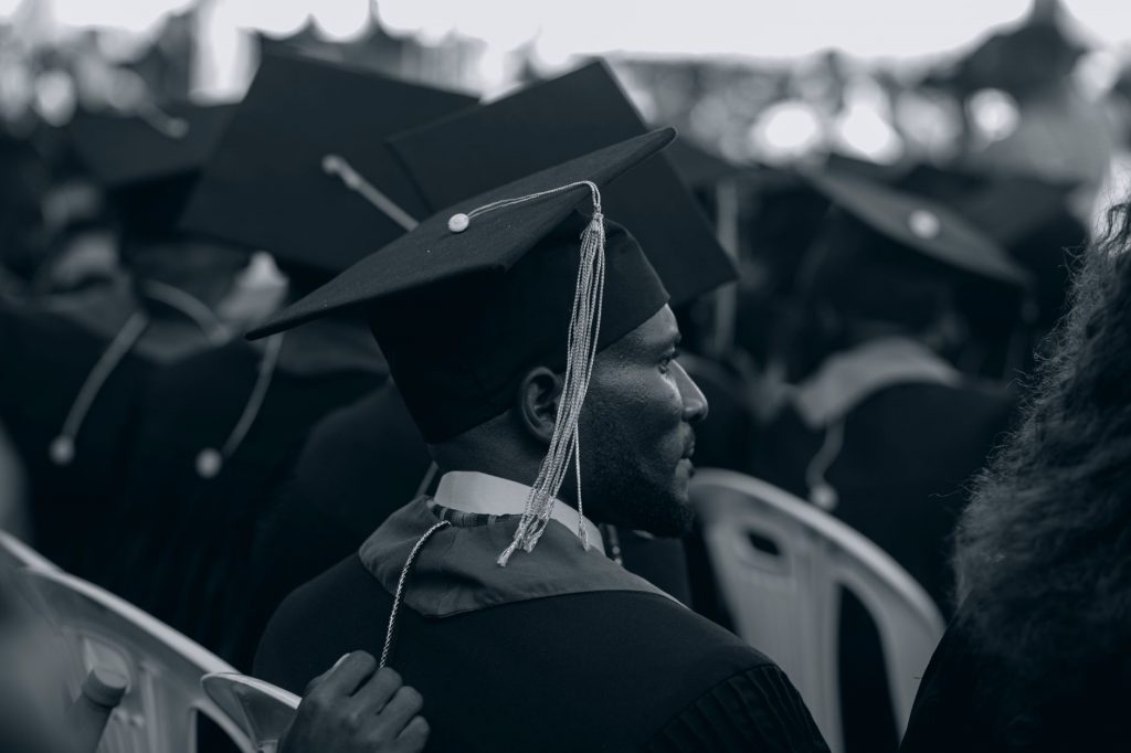 Black and white photo of graduates in caps and gowns at a ceremony.