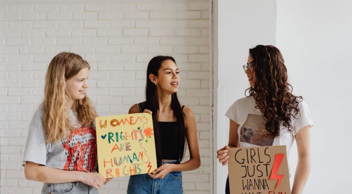 Three women holding advocacy signs supporting women's rights, indoors.