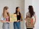Three women holding advocacy signs supporting women's rights, indoors.
