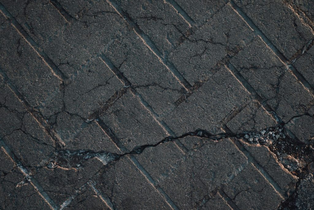 Close-up view of cracked urban pavement showing detailed texture and surface damage.