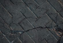 Close-up view of cracked urban pavement showing detailed texture and surface damage.
