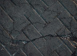 Close-up view of cracked urban pavement showing detailed texture and surface damage.