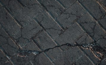 Close-up view of cracked urban pavement showing detailed texture and surface damage.