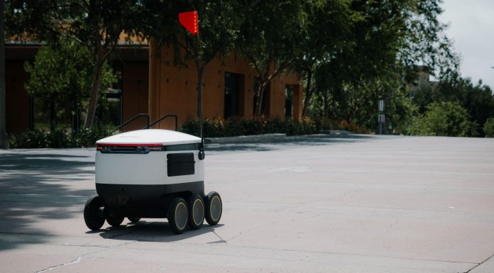 A sleek autonomous food delivery robot navigates a sunny urban landscape, showcasing modern innovation.