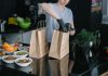 Hoboken’s Ready Strong Meals Brings Healthy Eating Home A person in a kitchen packing food ingredients into paper bags for takeout orders.