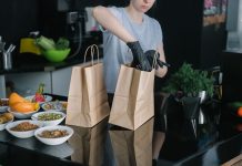 Hoboken’s Ready Strong Meals Brings Healthy Eating Home A person in a kitchen packing food ingredients into paper bags for takeout orders.