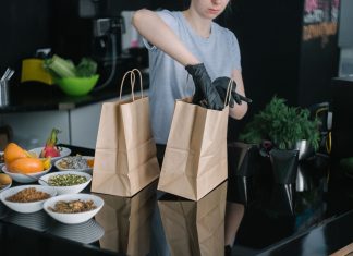 Hoboken’s Ready Strong Meals Brings Healthy Eating Home A person in a kitchen packing food ingredients into paper bags for takeout orders.