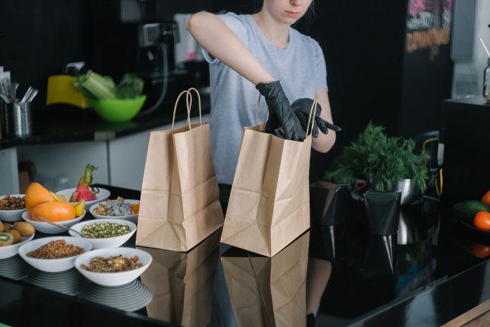 hoboken-s-ready-strong-meals-brings-healthy-eating A person in a kitchen packing food ingredients into paper bags for takeout orders.