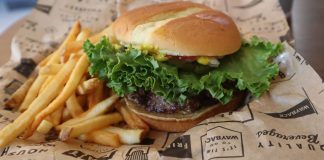 Tasty beef burger with French fries served on printed paper in Sacramento.
