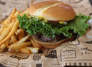 Tasty beef burger with French fries served on printed paper in Sacramento.