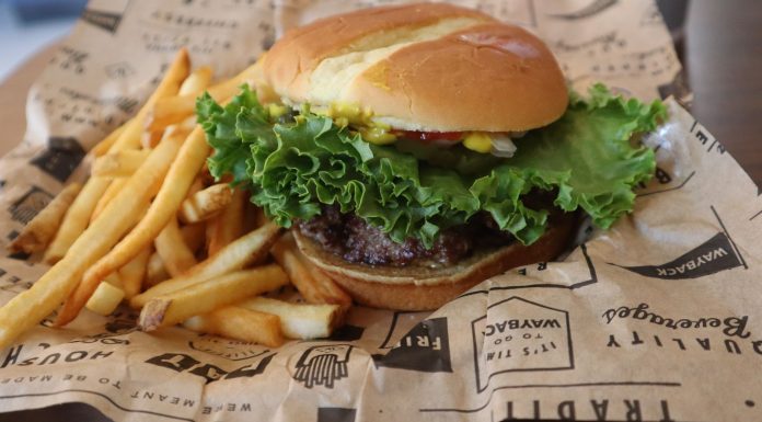 Tasty beef burger with French fries served on printed paper in Sacramento.