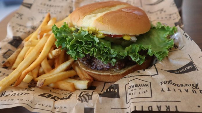 Tasty beef burger with French fries served on printed paper in Sacramento.