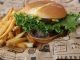 Tasty beef burger with French fries served on printed paper in Sacramento.