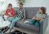 A family sits together on a sofa, discussing in a comfortable home setting, indicating a counseling session.