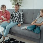 A family sits together on a sofa, discussing in a comfortable home setting, indicating a counseling session.