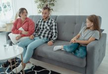 A family sits together on a sofa, discussing in a comfortable home setting, indicating a counseling session.