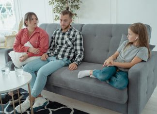 A family sits together on a sofa, discussing in a comfortable home setting, indicating a counseling session.
