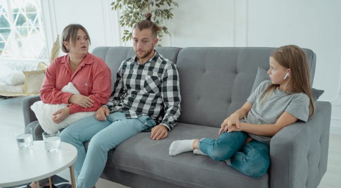 A family sits together on a sofa, discussing in a comfortable home setting, indicating a counseling session.