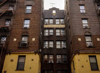 Low-angle view of urban brick apartment buildings with fire escapes, embodying classic city architecture.