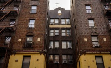 Low-angle view of urban brick apartment buildings with fire escapes, embodying classic city architecture.