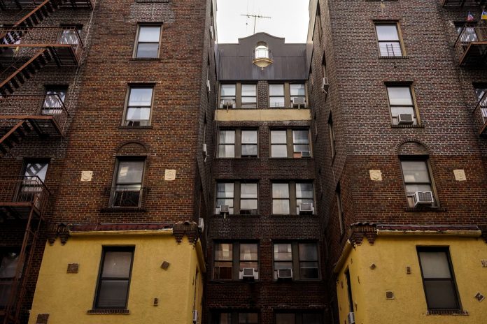 how-to-find-an-apartment-in-west-new-york-2026-gui Low-angle view of urban brick apartment buildings with fire escapes, embodying classic city architecture.