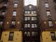 Low-angle view of urban brick apartment buildings with fire escapes, embodying classic city architecture.