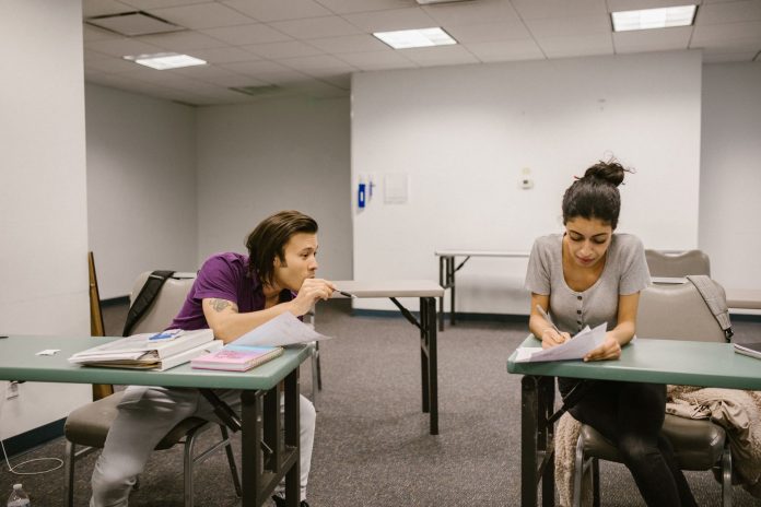 how-to-get-ged-north-bergen-nj-2026 Two college students in a classroom setting, one appears to be copying from the other's paper.