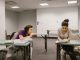 Two college students in a classroom setting, one appears to be copying from the other's paper.