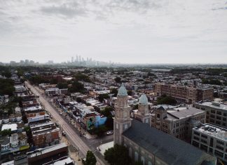 Aerial view showcasing Philadelphia's skyline and urban landscape with a historic church in the foreground.