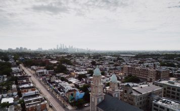 Aerial view showcasing Philadelphia's skyline and urban landscape with a historic church in the foreground.