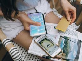 A woman uses her smartphone and credit card for online shopping while sitting outdoors.