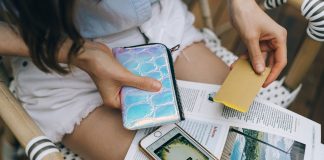 A woman uses her smartphone and credit card for online shopping while sitting outdoors.