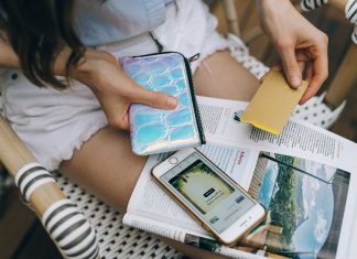A woman uses her smartphone and credit card for online shopping while sitting outdoors.