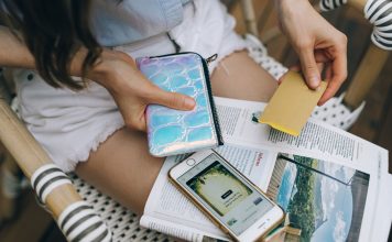 Jersey City Beats the Odds: Credit Card Debt Drops as Costs Rise A woman uses her smartphone and credit card for online shopping while sitting outdoors.