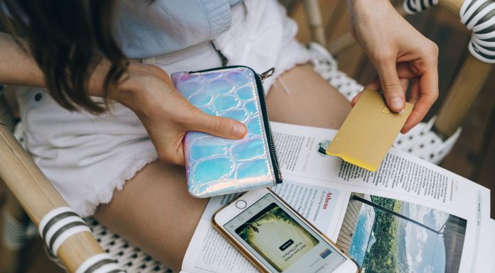 Jersey City Beats the Odds: Credit Card Debt Drops as Costs Rise A woman uses her smartphone and credit card for online shopping while sitting outdoors.