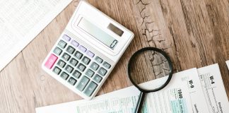 Tax forms laid out with a calculator and magnifying glass on a wooden surface, perfect for finance themes.