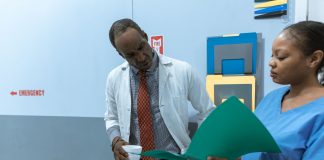 Jersey City Medical Center Doctors Ratify Contract After Year of Negotiations Doctors and nurse discussing medical charts in hospital setting.