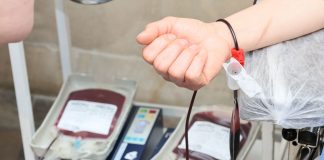 Close-up of blood donation process showing a donor's arm and blood bags in a clinic.